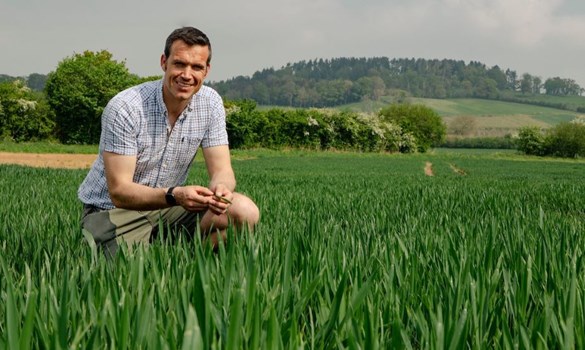 Chris Greenaway crouching in a field of wheat